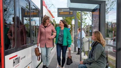 Reizigers lopen op tramhalte Reizigers lopen op halte naast HTM tram