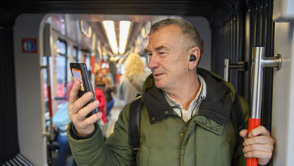 Man staat in tram Man staat in HTM tram en kijkt op telefoon