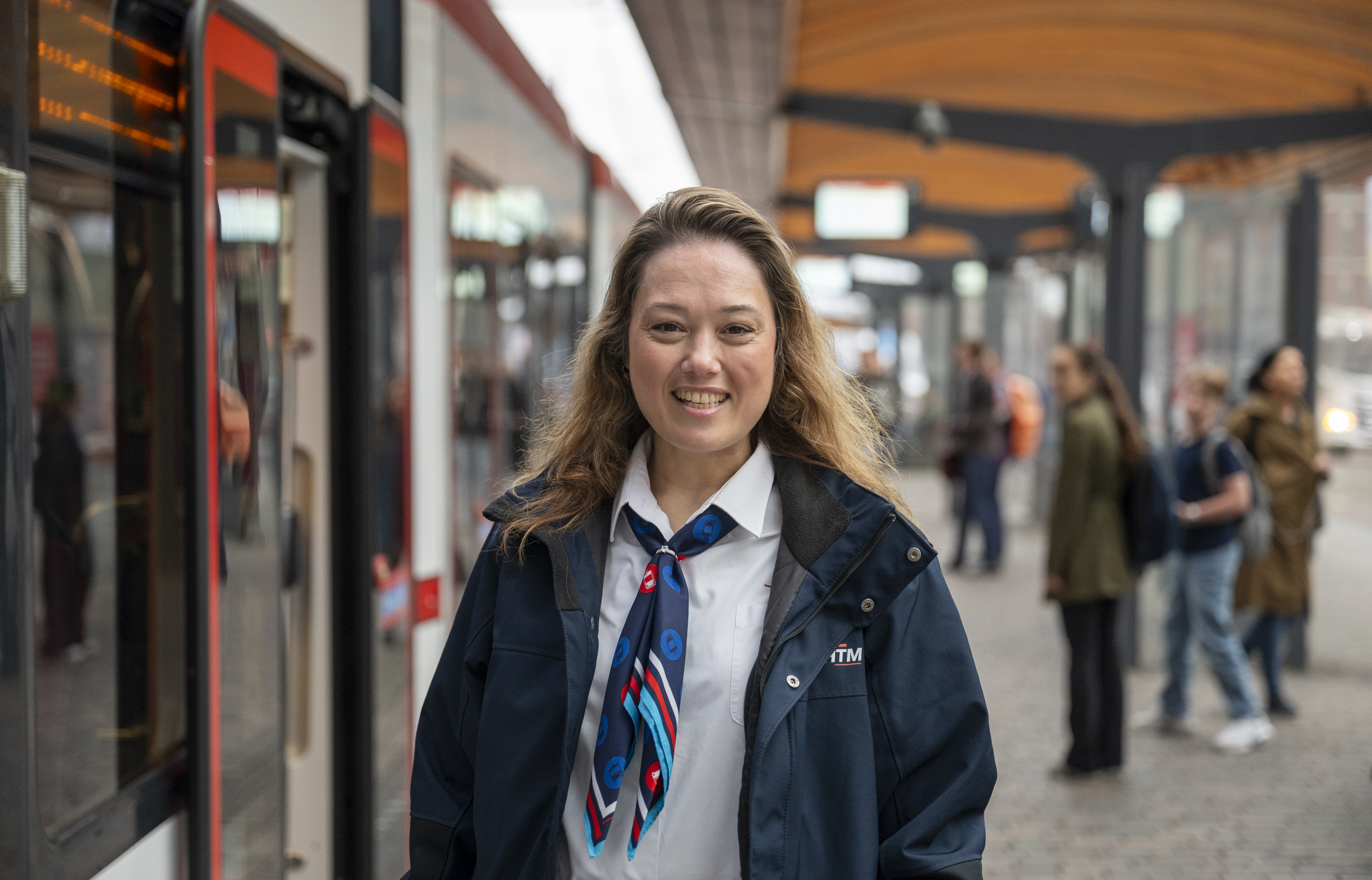 Lachende OV-steward staat op een HTM tramhalte