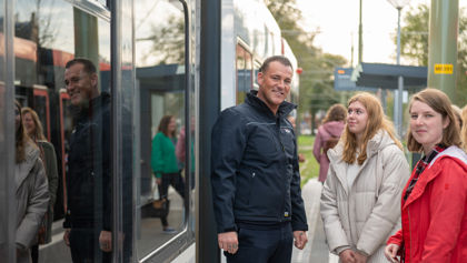 OV steward met twee reizigers naast tram HTM controleur met 2 reizigers naast HTM tram