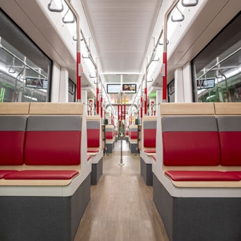 In de TINA zitten stoelen met rode bekleding en een licht houten afwerking In de TINA zitten stoelen met rode bekleding en een licht houten afwerking