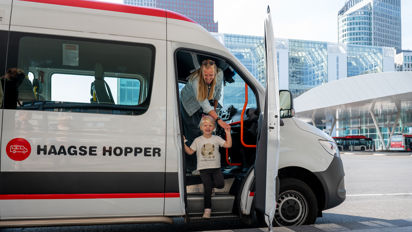 Een vrouw en klein kind stappen uit de Haagse Hopper op het busplatform Den Haag Centraal Foto van vrouw en kind die uit de Haagse Hopper stappen