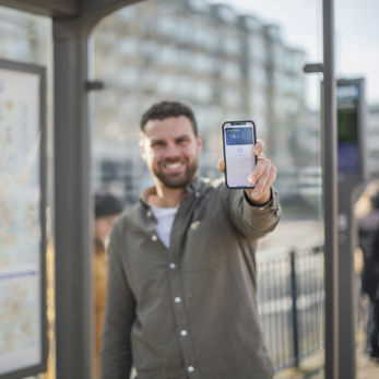 Man in bushokje die zijn mobile telefoon laat zien met daarop zijn betaalpas Man in bushokje die zijn mobile telefoon laat zien met daarop zijn betaalpas