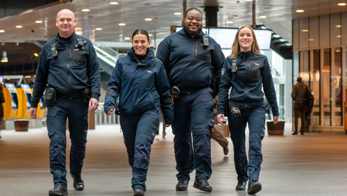 Lachende OV-stewards in de stationshal Den Haag Centraal Station Lachende OV-stewards naast elkaar