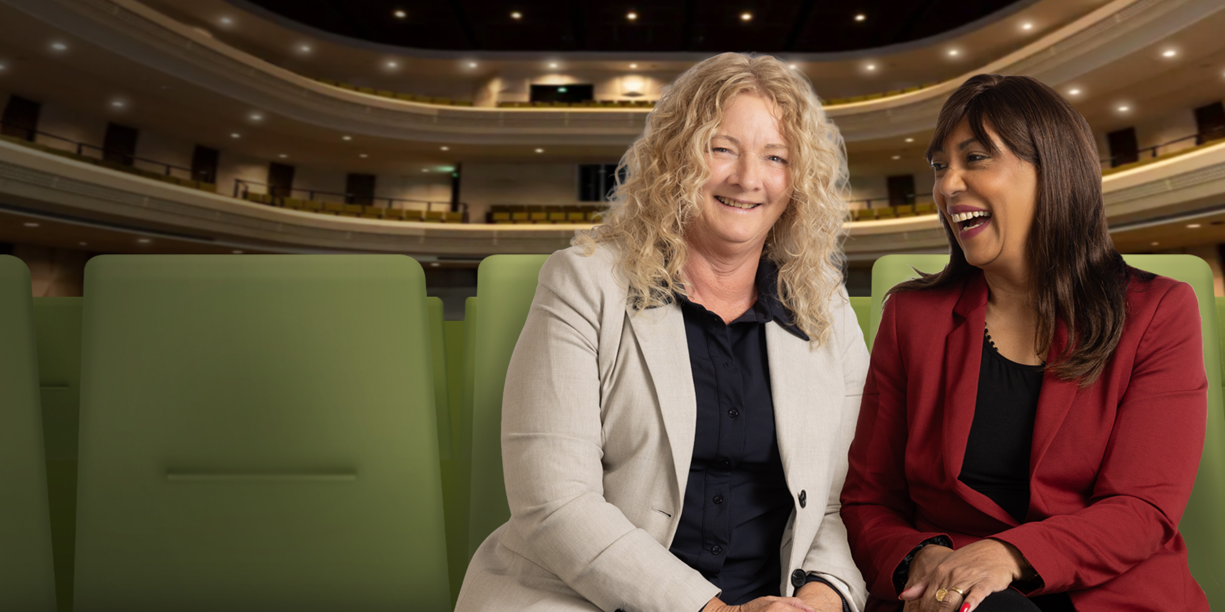 Twee vrouwen zitten gezellig in het theater lachend naar elkaar