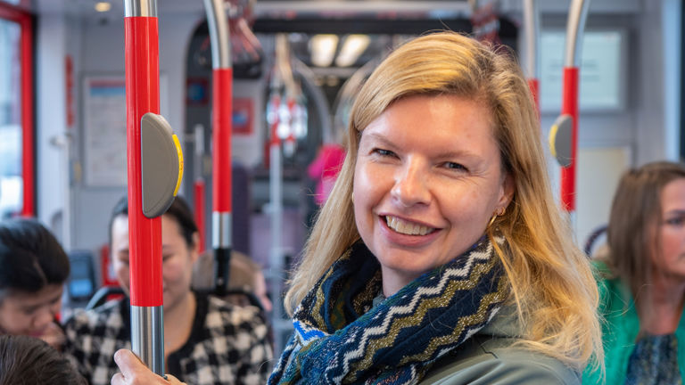 Reiziger in HTM tram Reiziger staat in HTM tram en lacht naar de camera